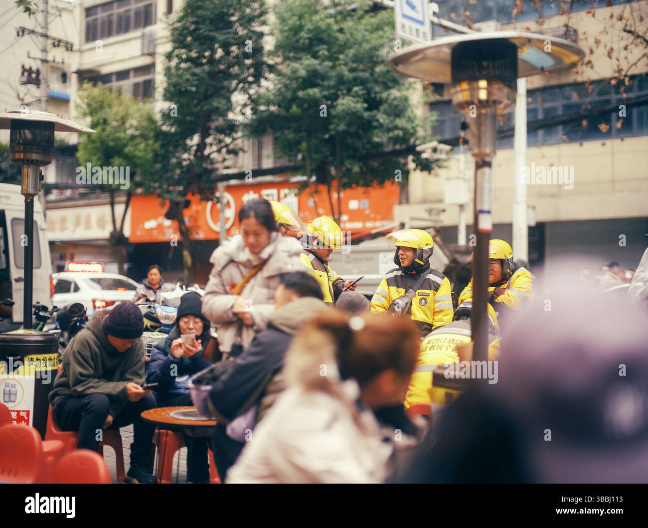 Meituan Delivery Riders and Diners at a Bustling Wuhan Street Food Stall - Hubei, China Stock Photo