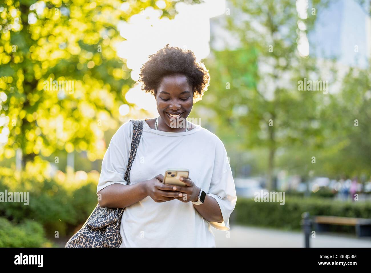 Smiling young woman using mobile phone in the city Stock Photo