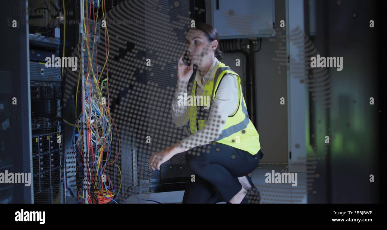 Kneeling female tech wearing yellow vest routing network cables in data ...