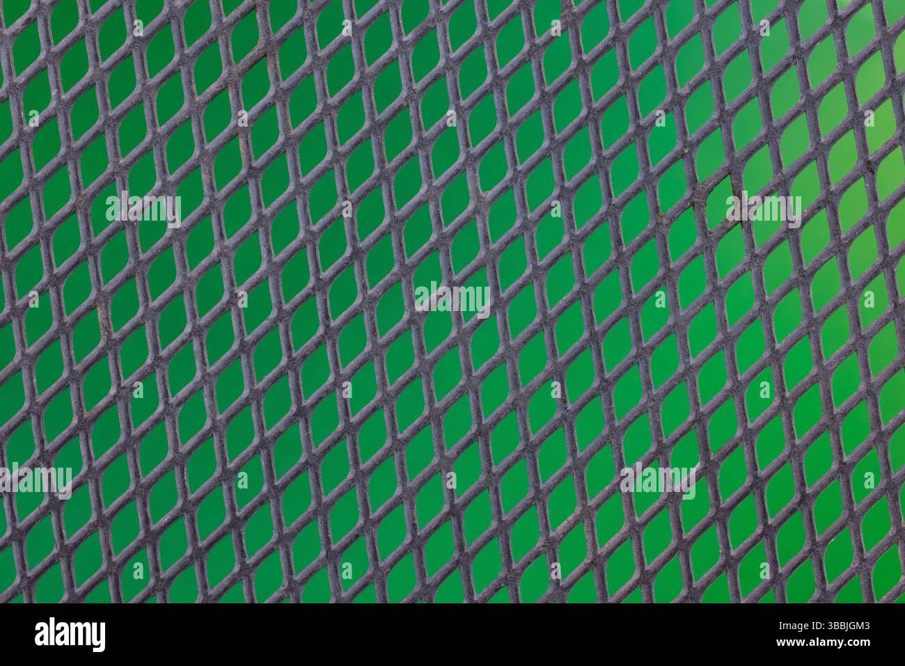 A black metal mesh with green background. Stock Photo