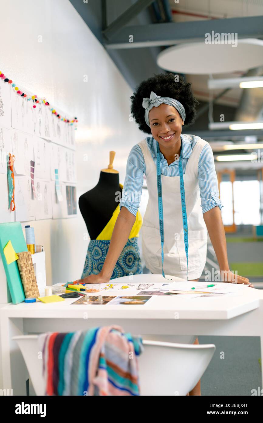 Leaning forward African American fashion designer sketching on studio ...