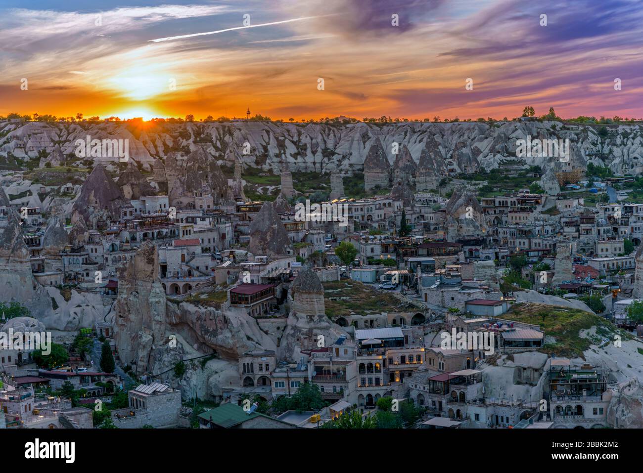 The sun sets over a dense field of fairy chimneys and houses in ...