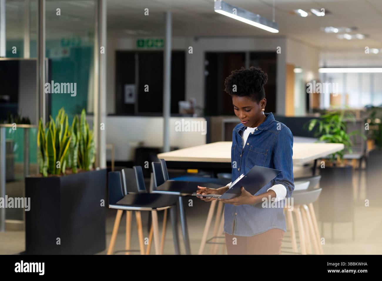 African American woman examining documents at table in modern office ...