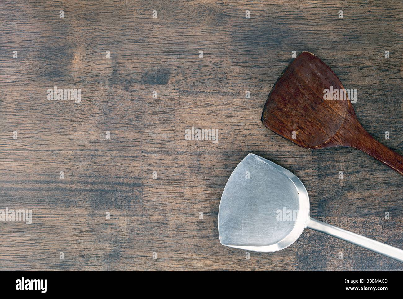 A wooden and metal spatulas on rustic wooden table, showcasing blend of natural and industrial materials. contrast highlights versatility and function Stock Photo