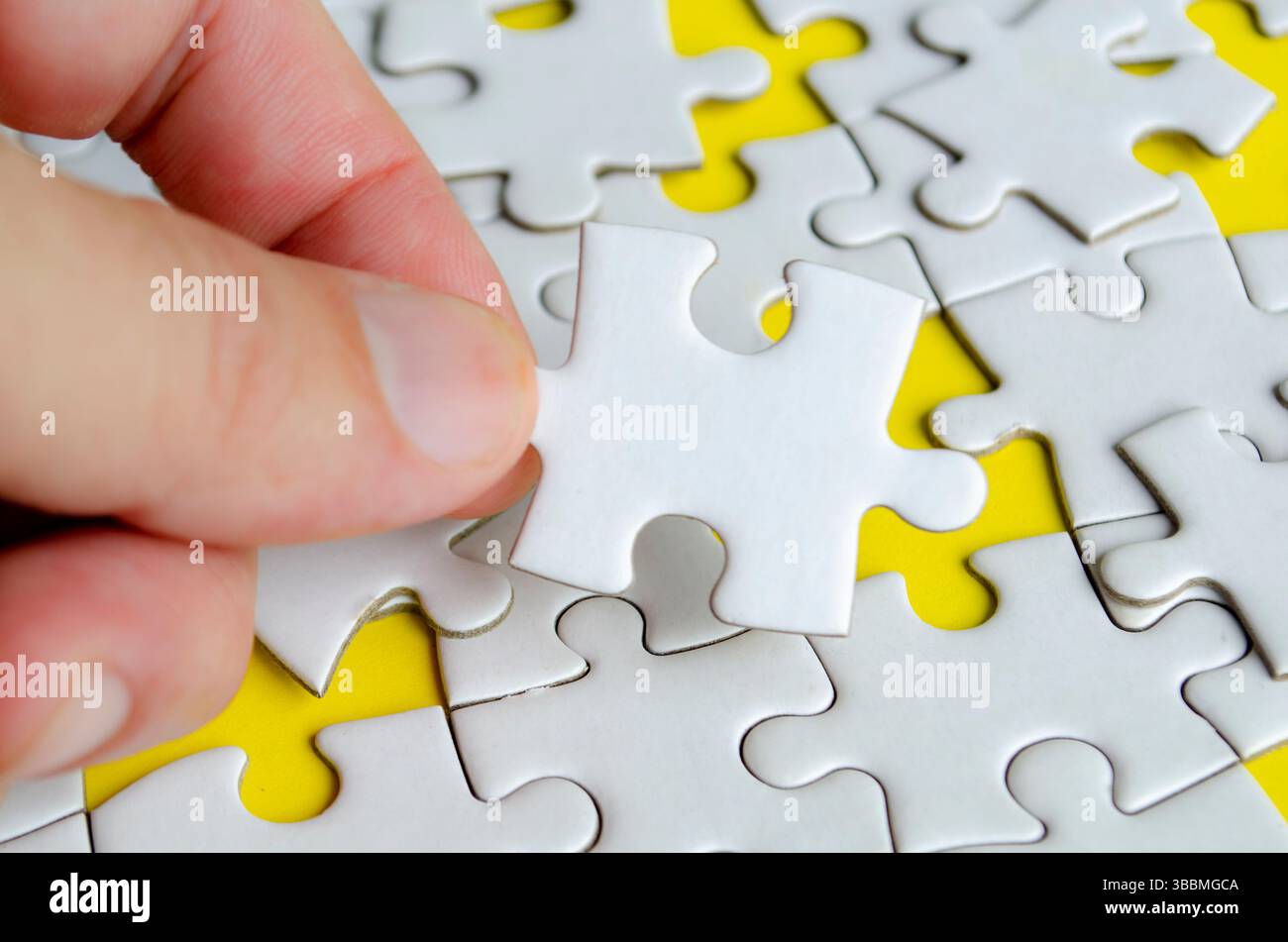 Close up of hand place missing jigsaw puzzle representing problem solving skill. Stock Photo