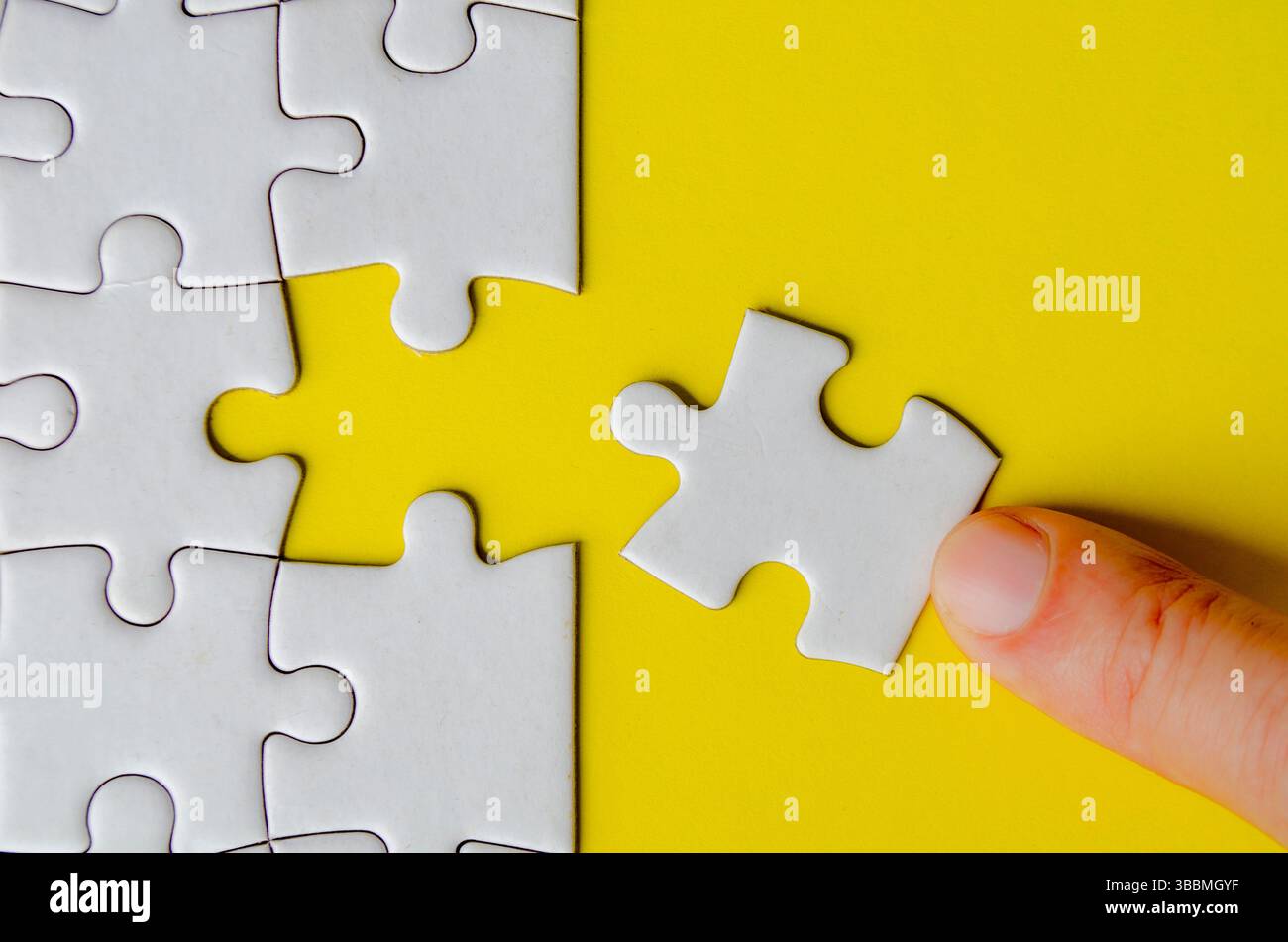 Hand fitting a missing white jigsaw pieces. Stock Photo