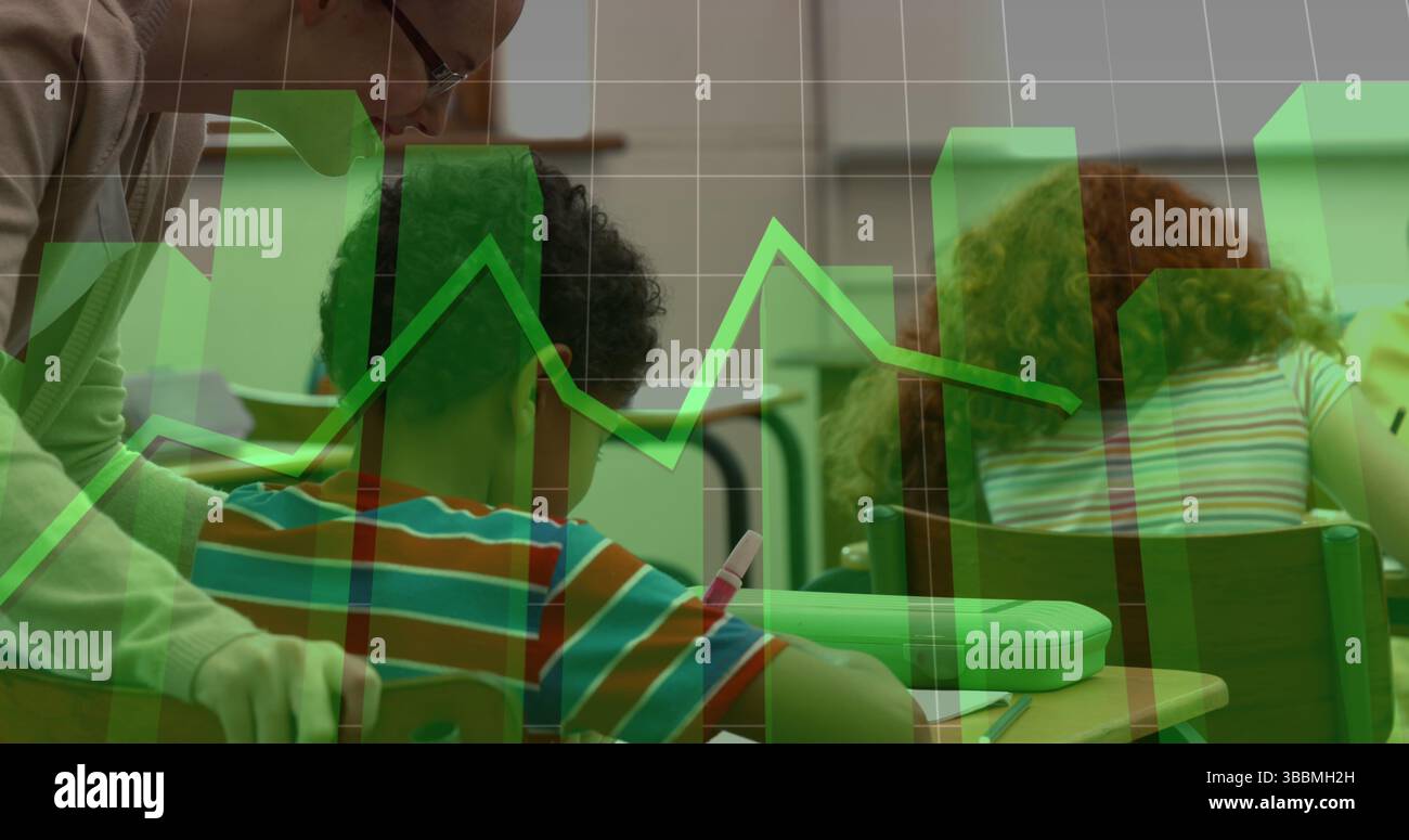 Assisting teacher guiding boy writing on worksheets in classroom, green graph overlay Stock Photo