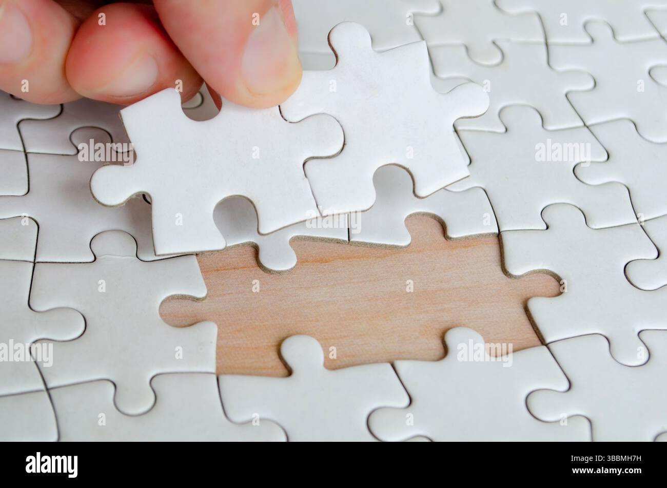 Hand placing missing jigsaw puzzle pieces. Solution concept. Stock Photo