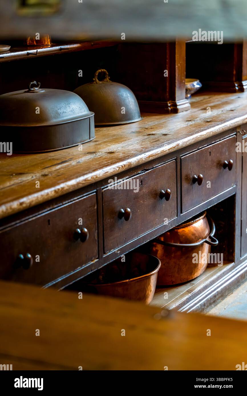 Georgian oak Welsh dresser displaying wrought-iron cloches and hammered copper vessels on inset-drawer shelving Stock Photo