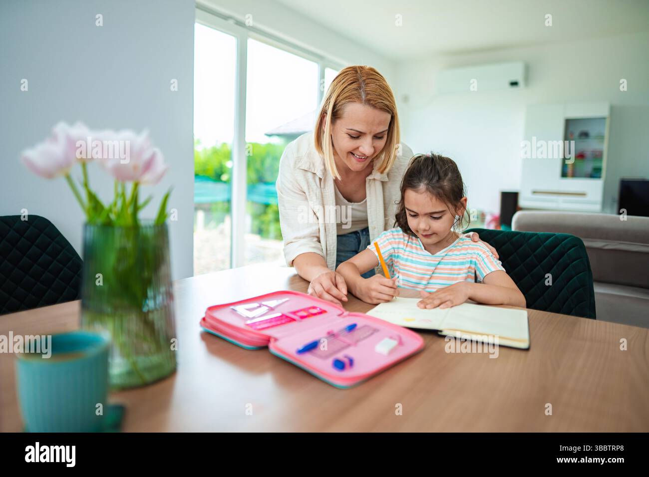 A mother helps her daughter with homework at the table Stock Photo - Alamy