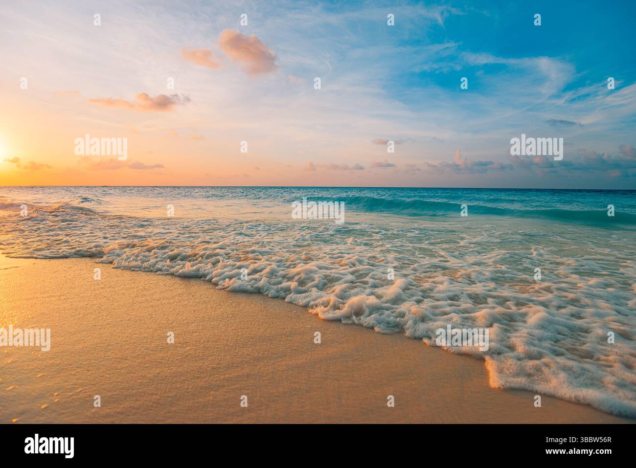 Serene views. Gorgeous sunset beach with calm waves and colorful sky, soft clouds over tranquil ocean seascape, peaceful tropical evening nature scene Stock Photo