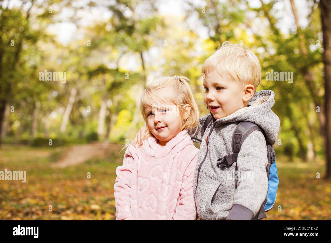 Children on a walk in autumn park. Lovely siblings on happy family vacation in forest Stock Photo
