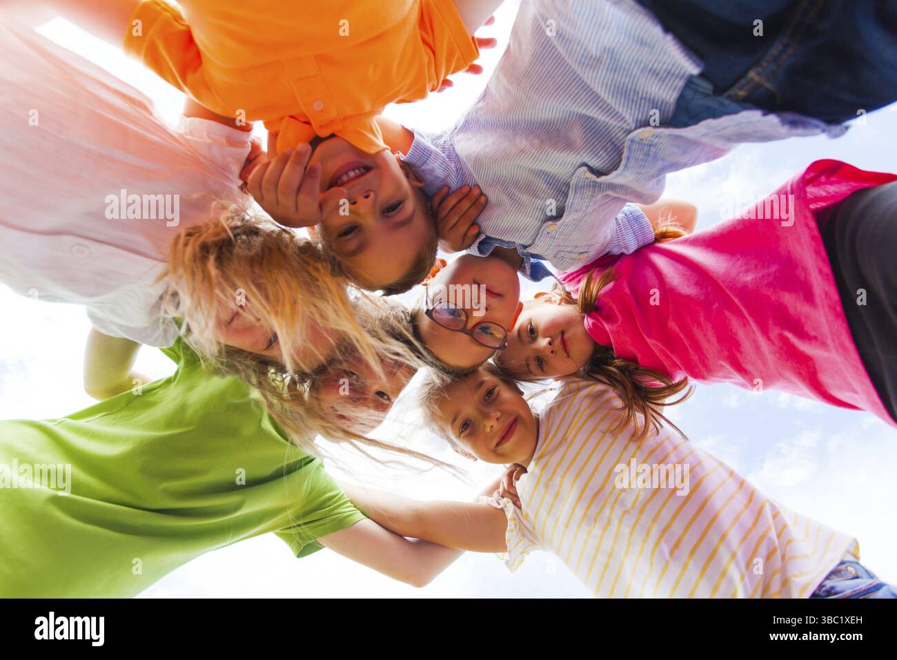 A huddle of school kids in colorful t-shirt standing shoulder to ...