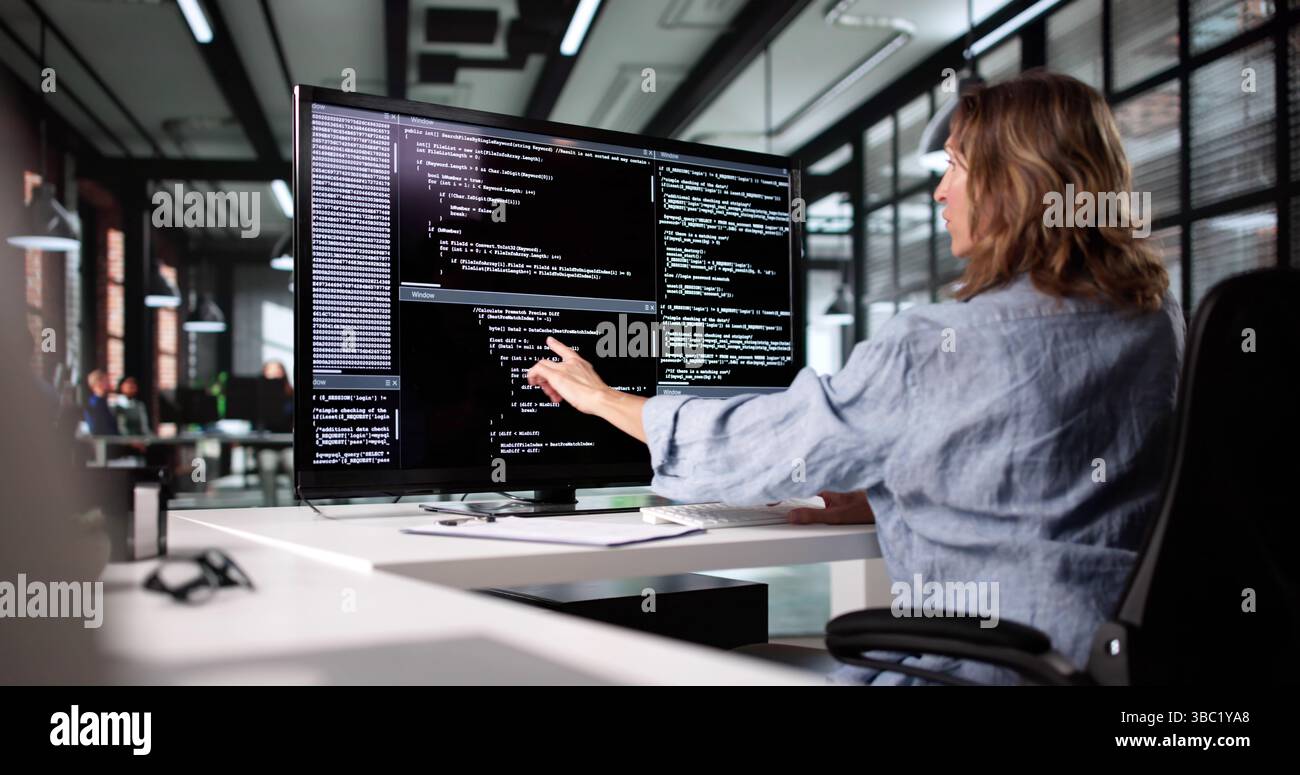 Female Web Developer Working On Software Code At Office Desk Stock Photo
