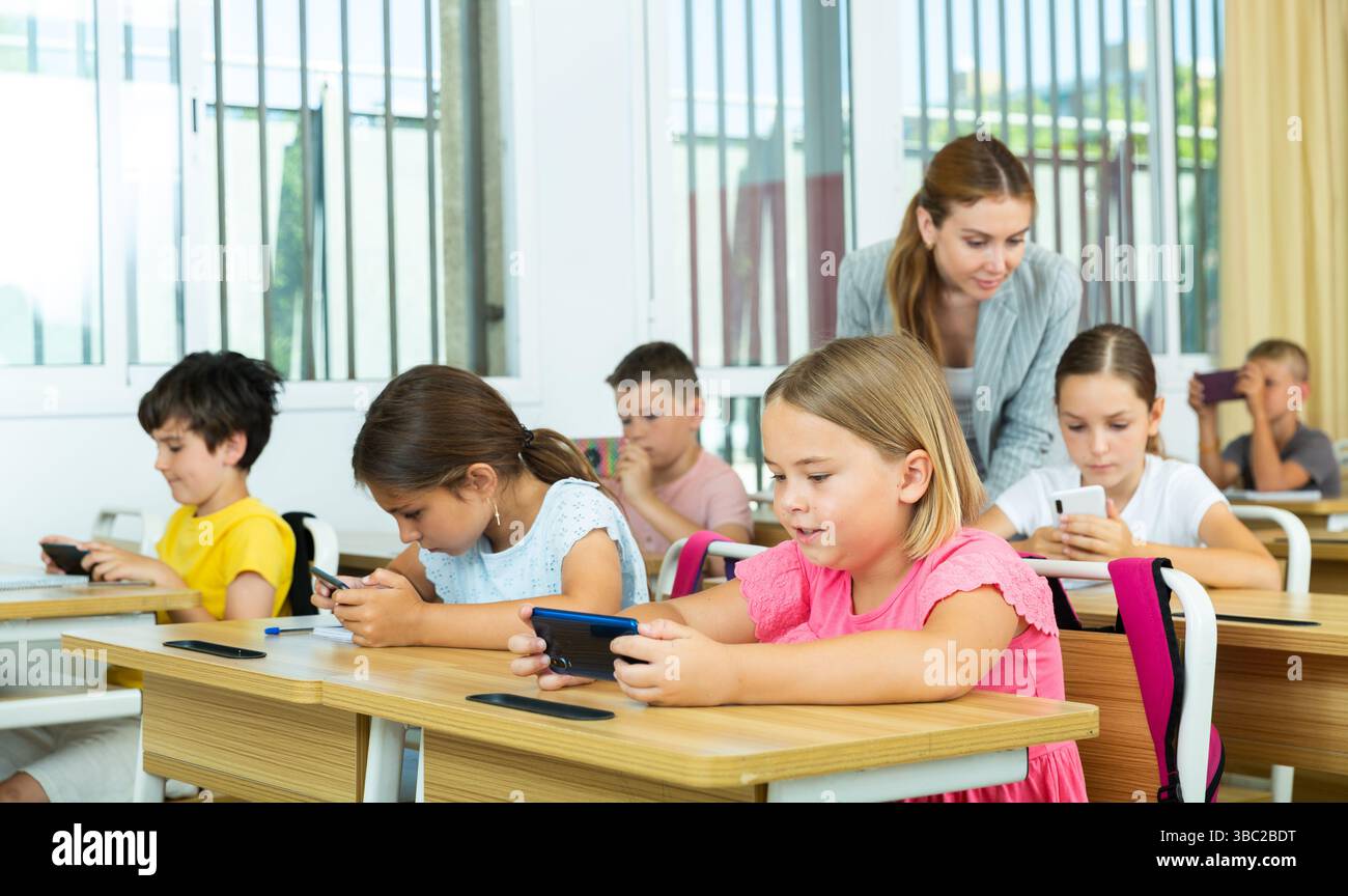 Pupils using mobile phones during lesson in school Stock Photo