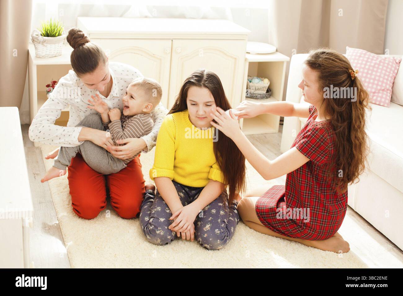 Three girls doing hair sitting on the floor in the room Stock Photo - Alamy