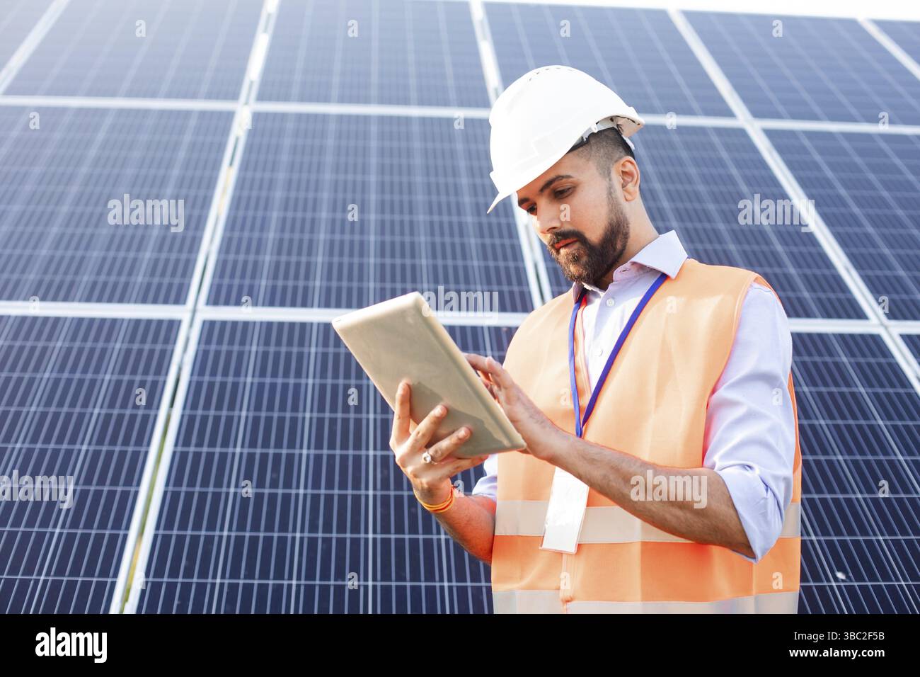 Male indian engineer in uniform stands against the backdrop of a solar ...
