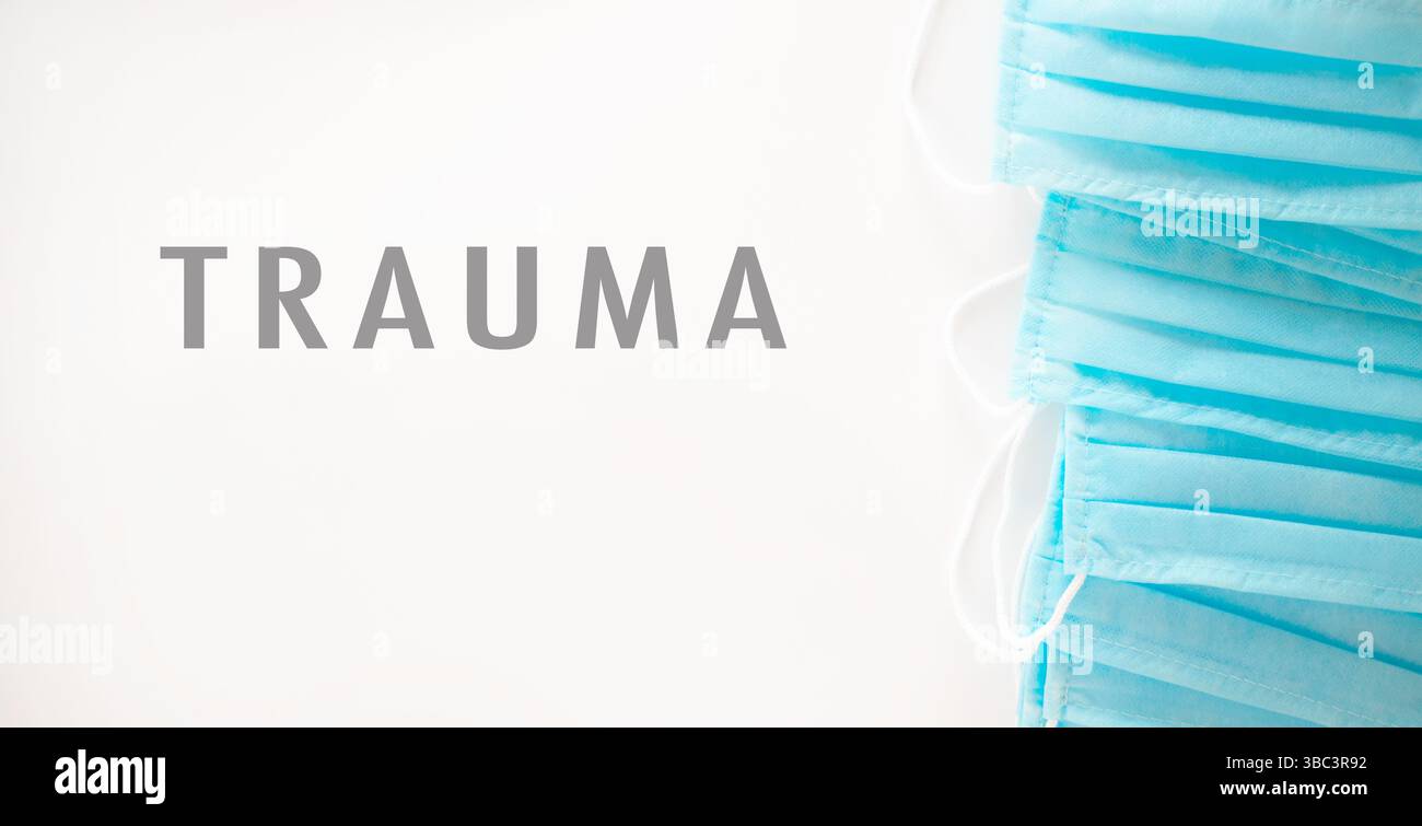 Stack of blue surgical masks with the word trauma written underneath. Concept of urgency and seriousness Stock Photo