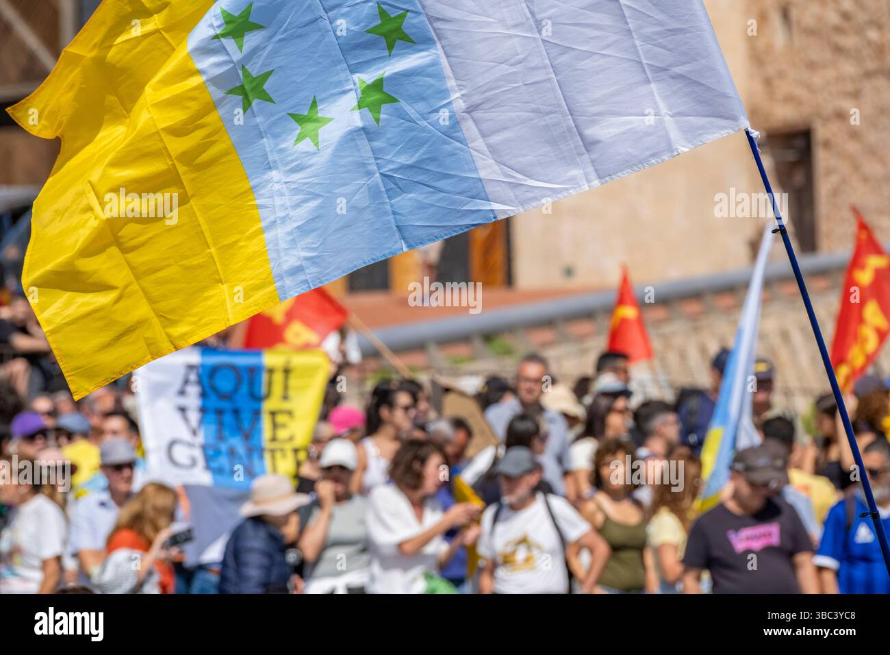 Gran Canaria, Canary Islands, Spain, 18th May 2025. Thousands of locals march along the seafront overlooking the city beach in Las Palmas, the capital of Gran Canaria. One of many protests throughout the Canary Islands calling for a freeze on tourist numbers and a more sustainable tourism policy. Holiday rental homes are also making it difficult for some locals to afford to rent property. PICTURED: A man holds a Canary Islands flag saying; people live here. Credit: Alan Dawson/Alamy Live News Stock Photo