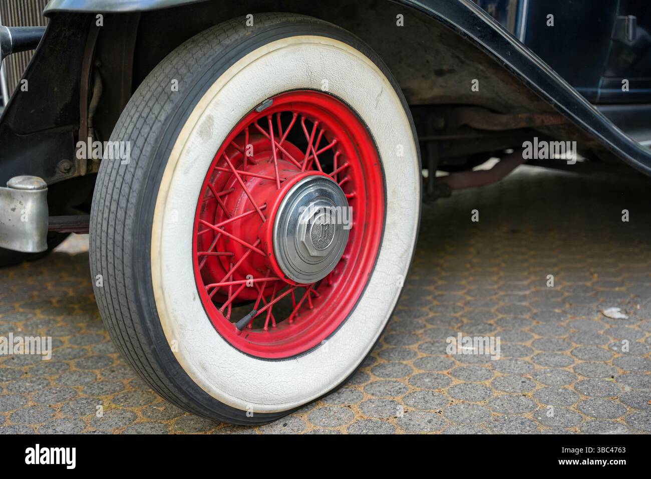 Germany Berlin May 11, 2025. Red spoked wheel with whitewall tires. Detailed view of a classic red spoked wheel with striking whitewall tires. The com Stock Photo
