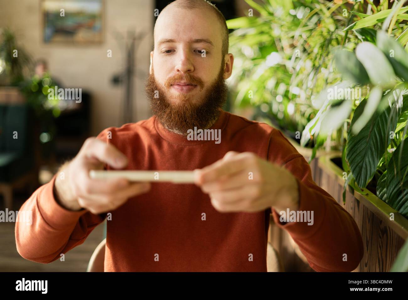 Bearded redhead man scanning remote check deposit while using mobile phone Stock Photo
