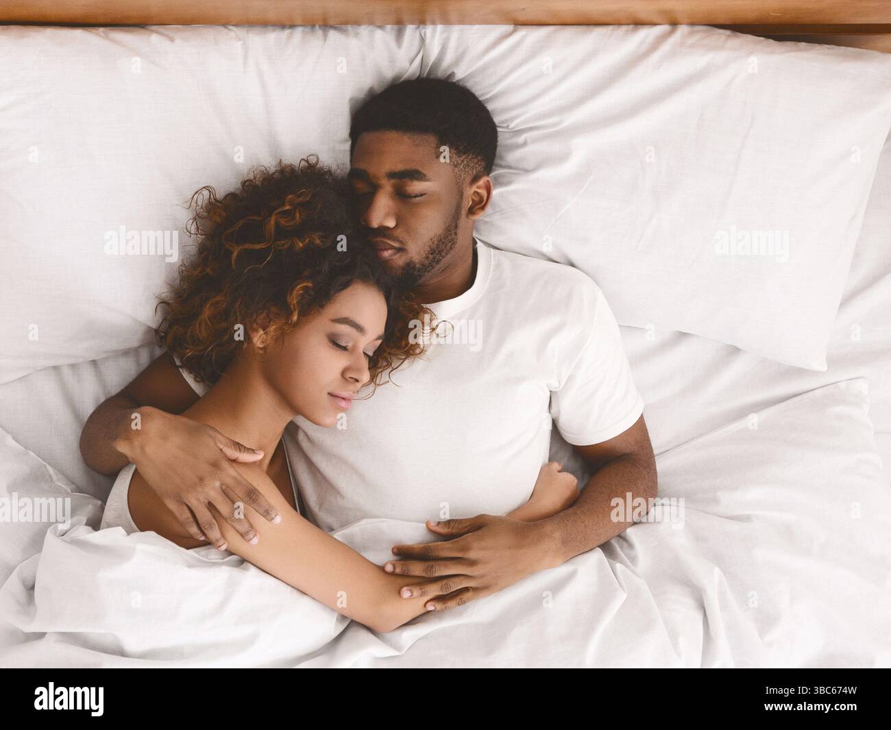 Young black couple sleeping together in bed Stock Photo - Alamy