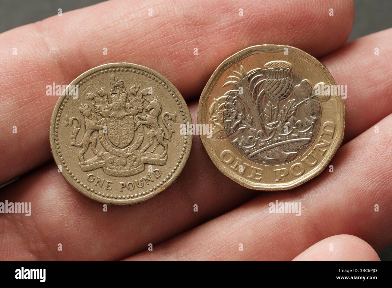 Close-up comparison of old and new one pound coins held in hand, highlighting the evolution of British currency design and security features, Stafford Stock Photo