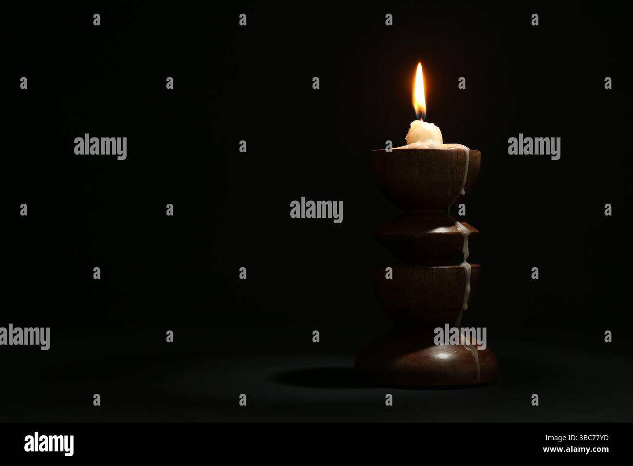 Burning candle in candlestick on black background, space for text Stock ...