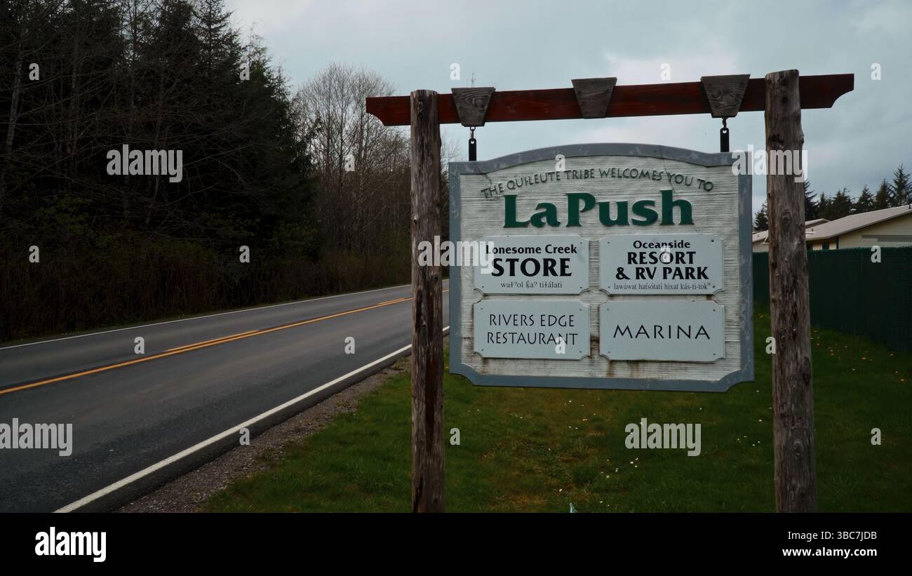FORKS, USA - APRIL 12, 2017 -  Rustic wooden welcome sign to La Push, Washington, with road, trees, and cloudy sky Stock Photo