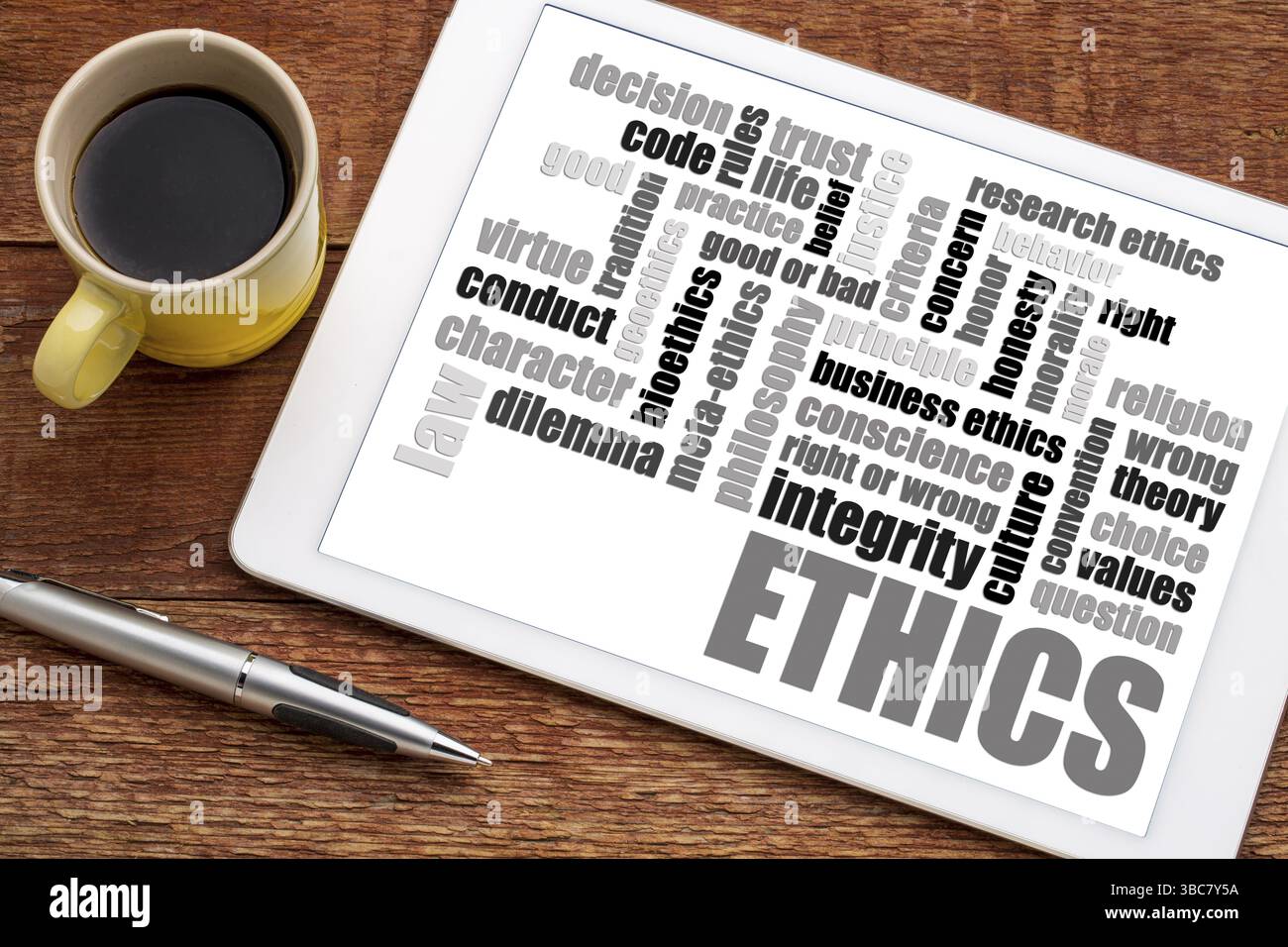 Ethics and moral dilemma word cloud on a digital tablet with a cup of coffee Stock Photo