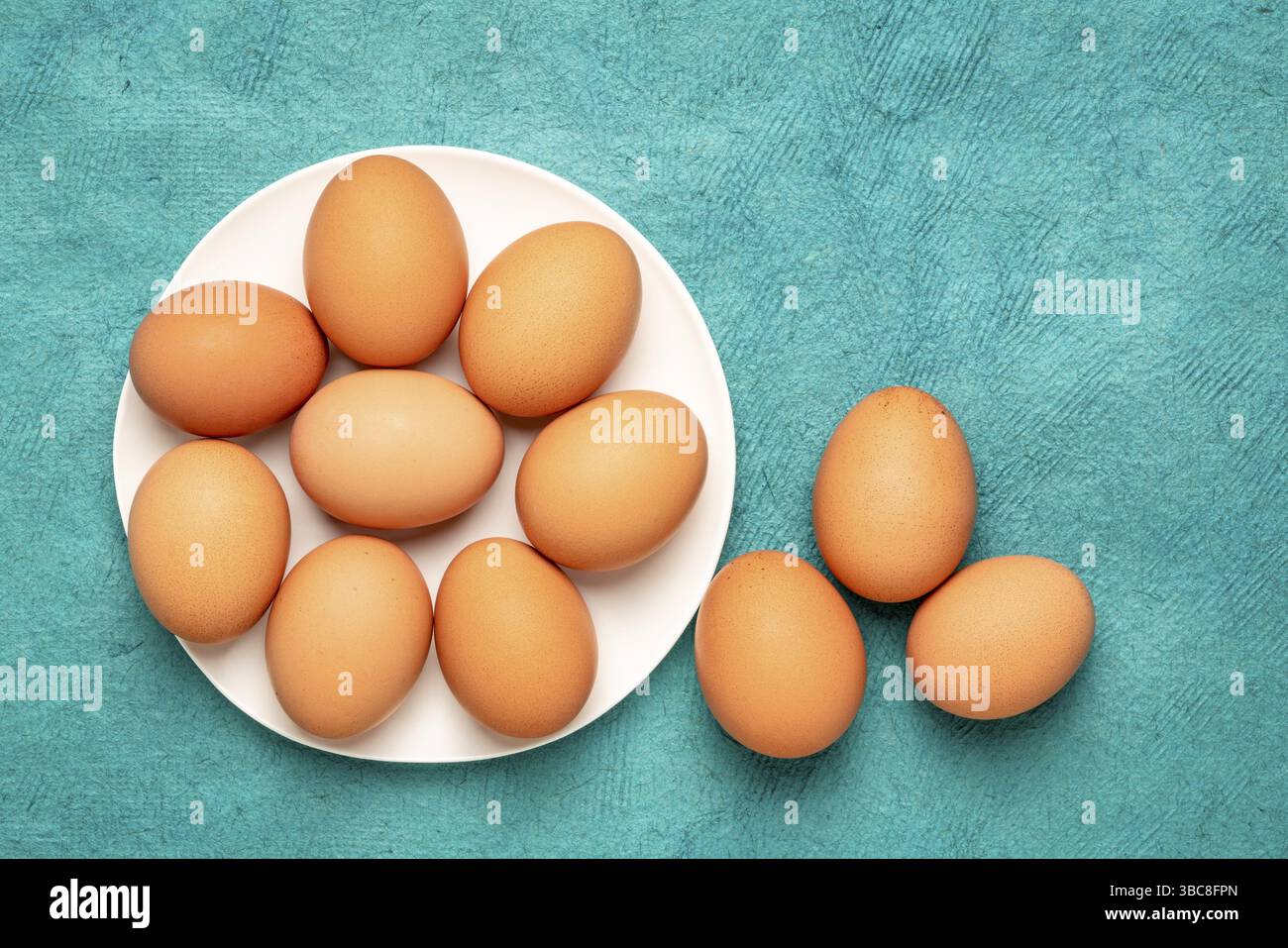 Free-range large brown chicken eggs on a white plate against textured bark paper with a copy space Stock Photo