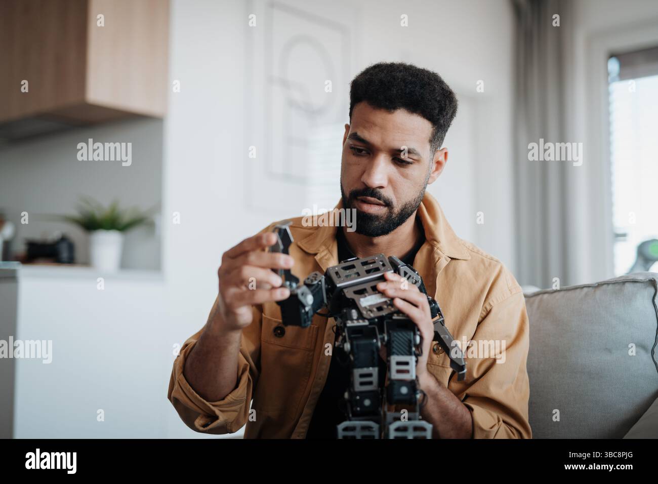 Handsome engineer student working on robot project at home. Stock Photo