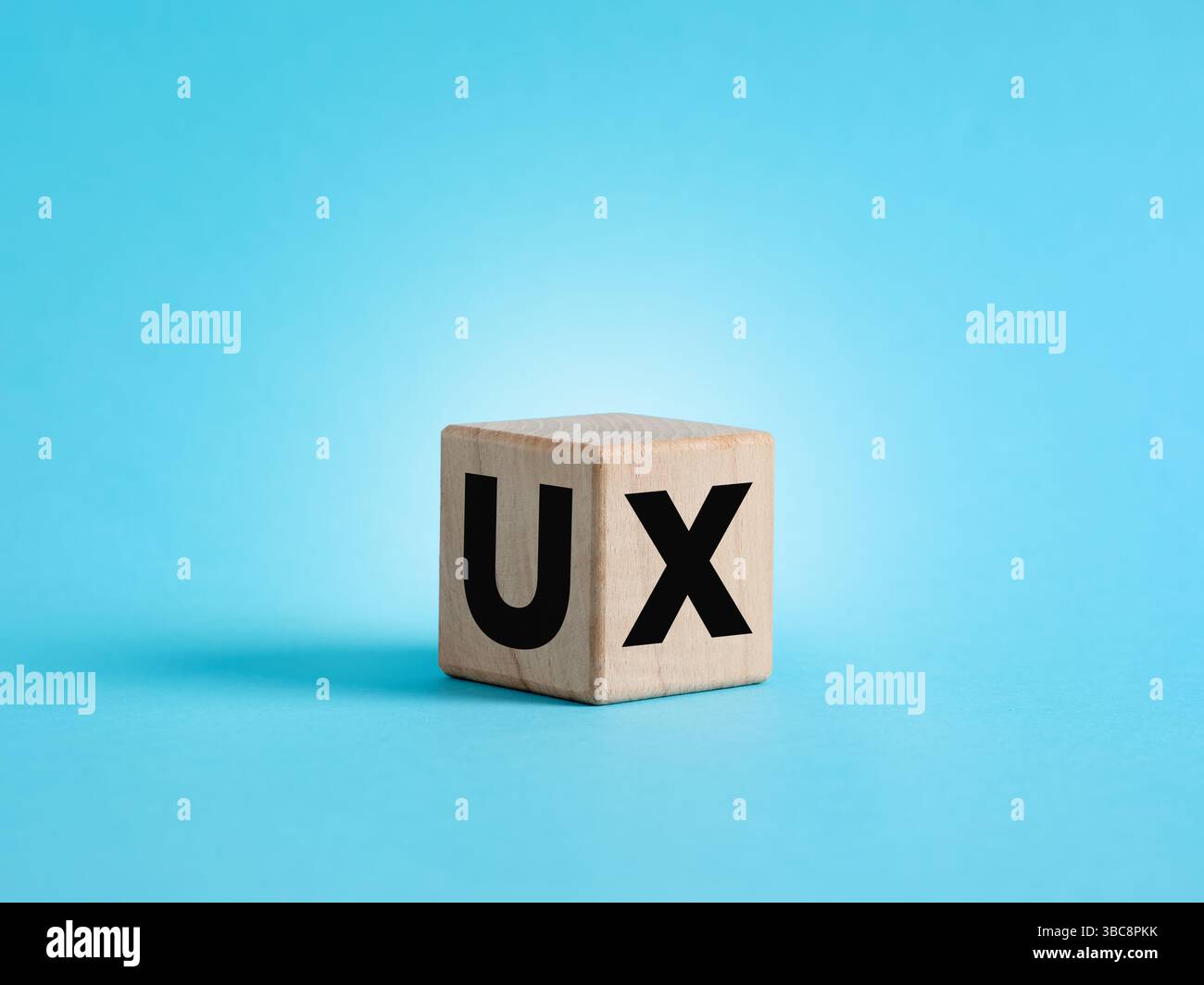 Wooden cube showing the acronym UX, user experience, on blue background, user interface design concept Stock Photo