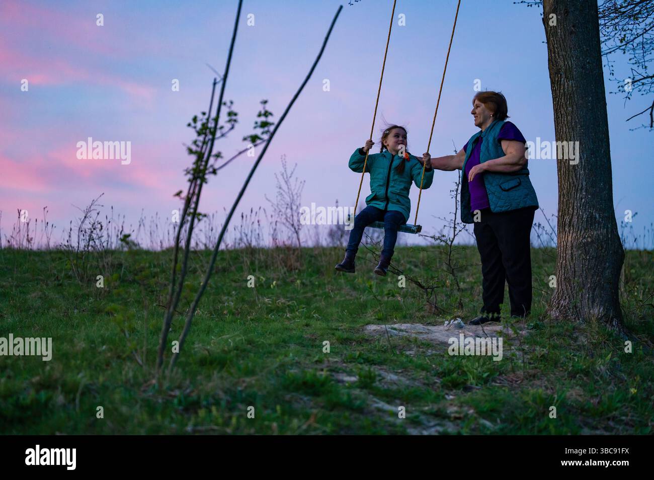 Grandmother and granddaughter enjoying a sunset swing ride Stock Photo ...