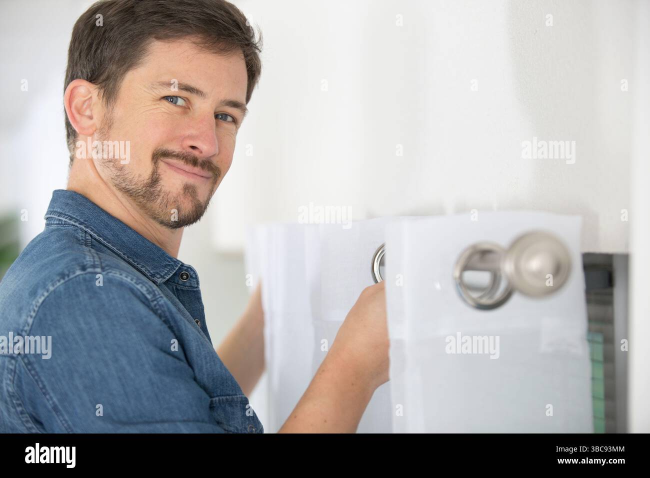 handyman services - worker installing window curtain rod Stock Photo