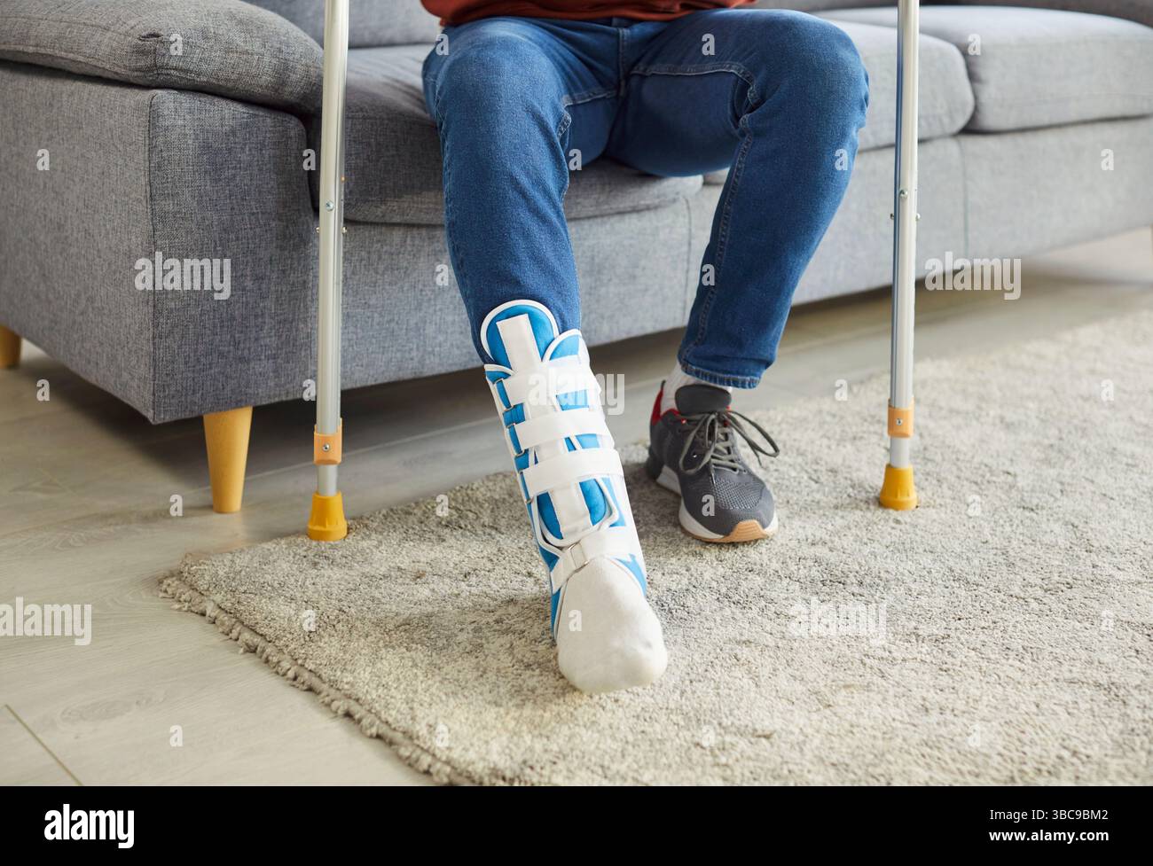 Cropped image of man wearing cast on leg, trying to walk with crutches in house Stock Photo