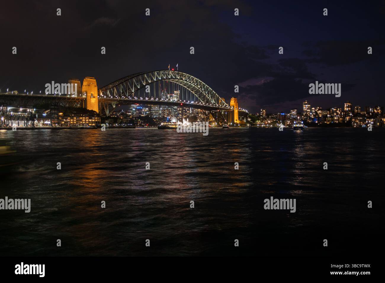 Sydney Harbour Bridge illuminated at night with city lights behind ...