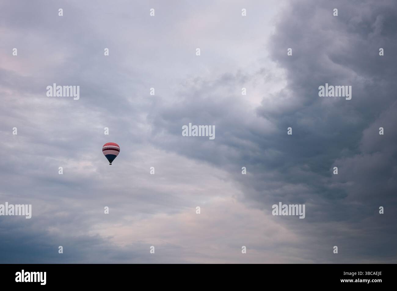 Hot air balloon flying under dramatic cloudy sky Stock Photo - Alamy
