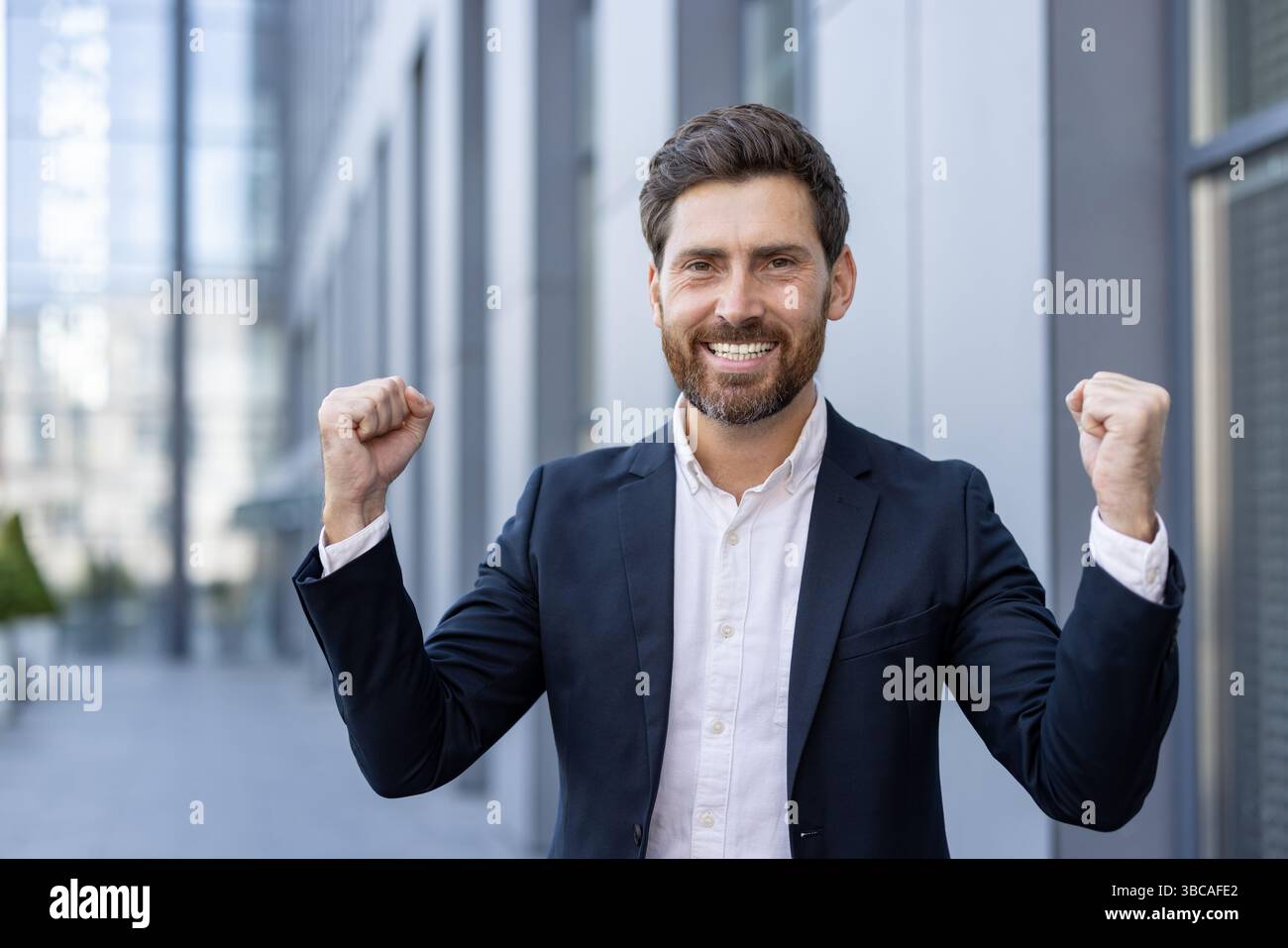 A happy businessman celebrates success with clenched fists outside a ...