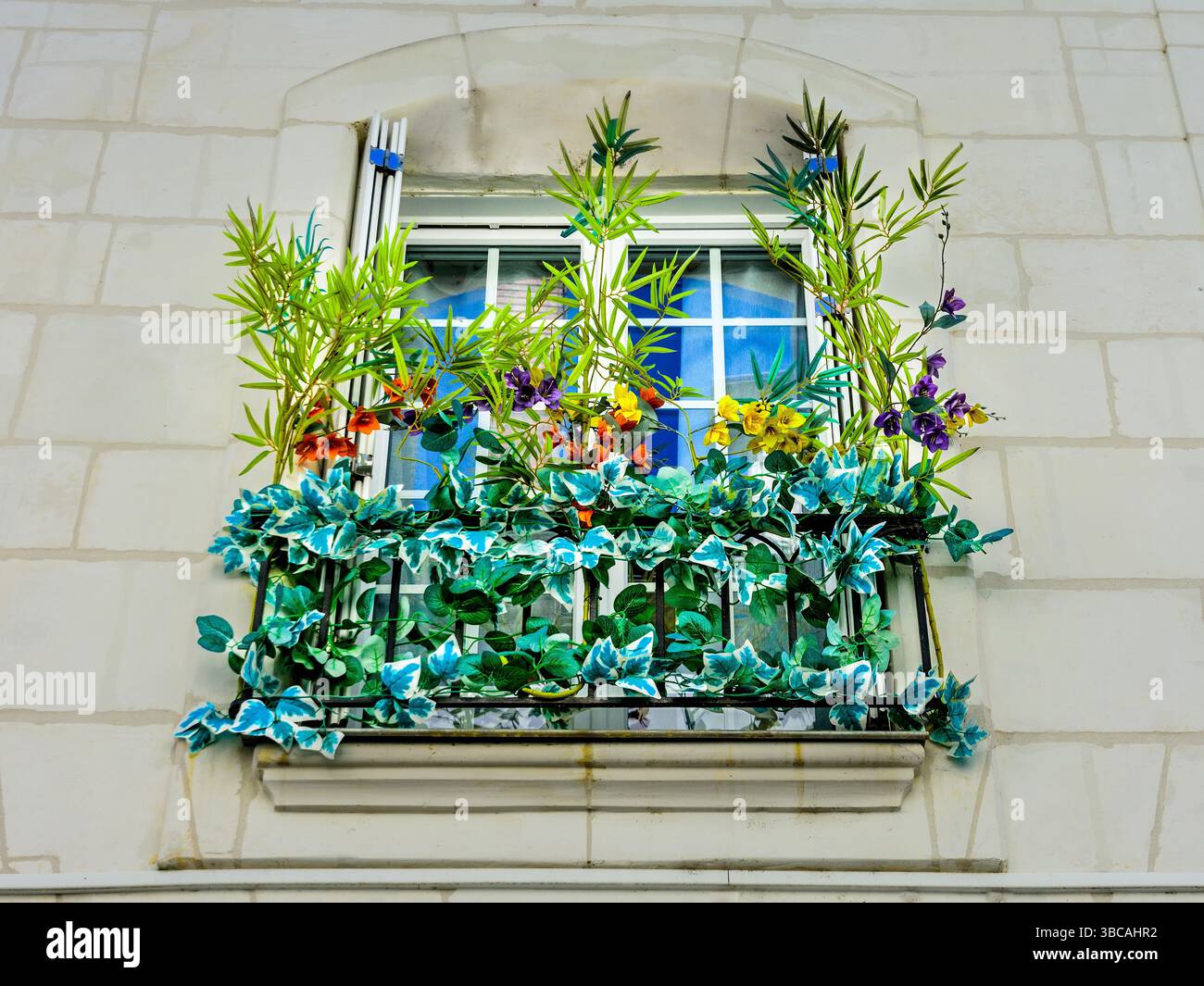 Artificial flower arrangement on upper floor window balcony - Loches, Indre-et-Loire (37), France. Stock Photo