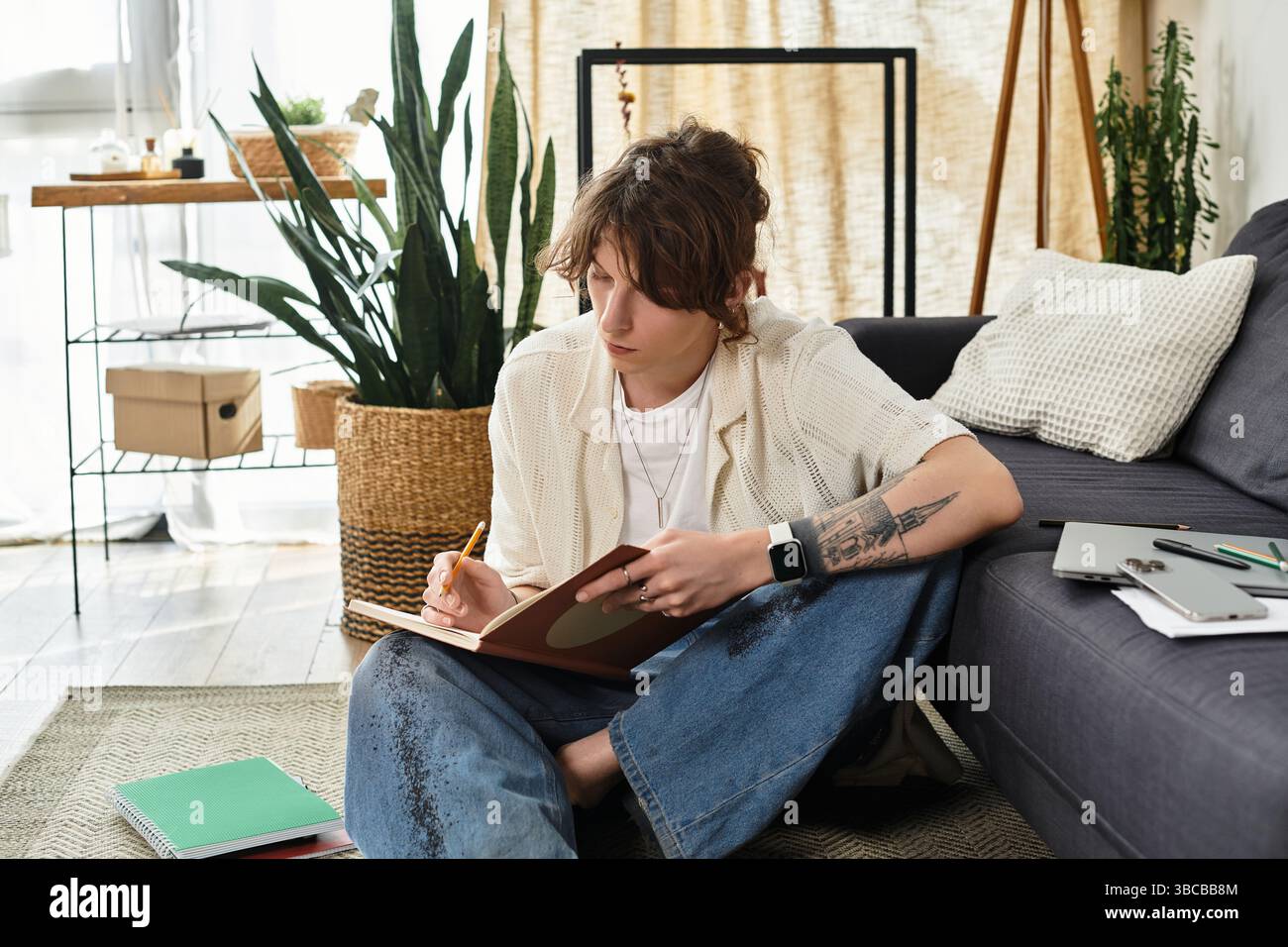 Focused student surrounded by study materials practices creativity at home while jotting down ideas. Stock Photo
