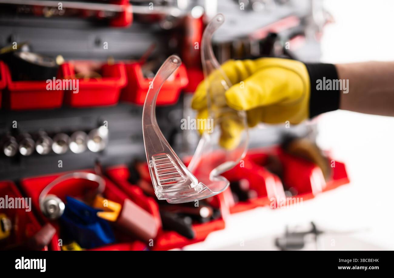 Mechanic Holds Protective Goggles For Eye Protection During Auto Service Stock Photo