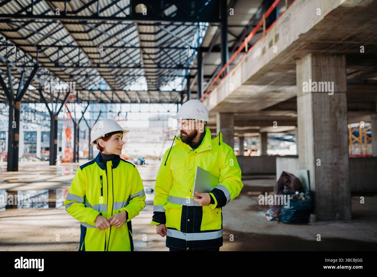 Engineers discussing construction plans using a tablet on site. Stock Photo