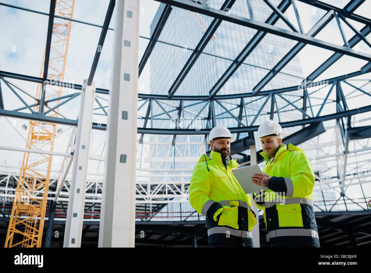 Construction managers using digital tablet on site, reviewing project plans. Stock Photo