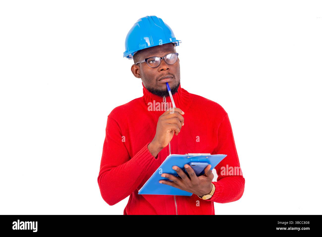 a man engineer wearing safety helmet standing on white background thinking while holding a notepad. Stock Photo