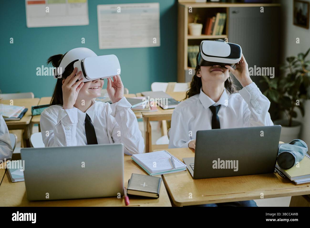 Students experiencing virtual reality in classroom setting while wearing headsets and interacting with laptops, demonstrating technology integration i Stock Photo