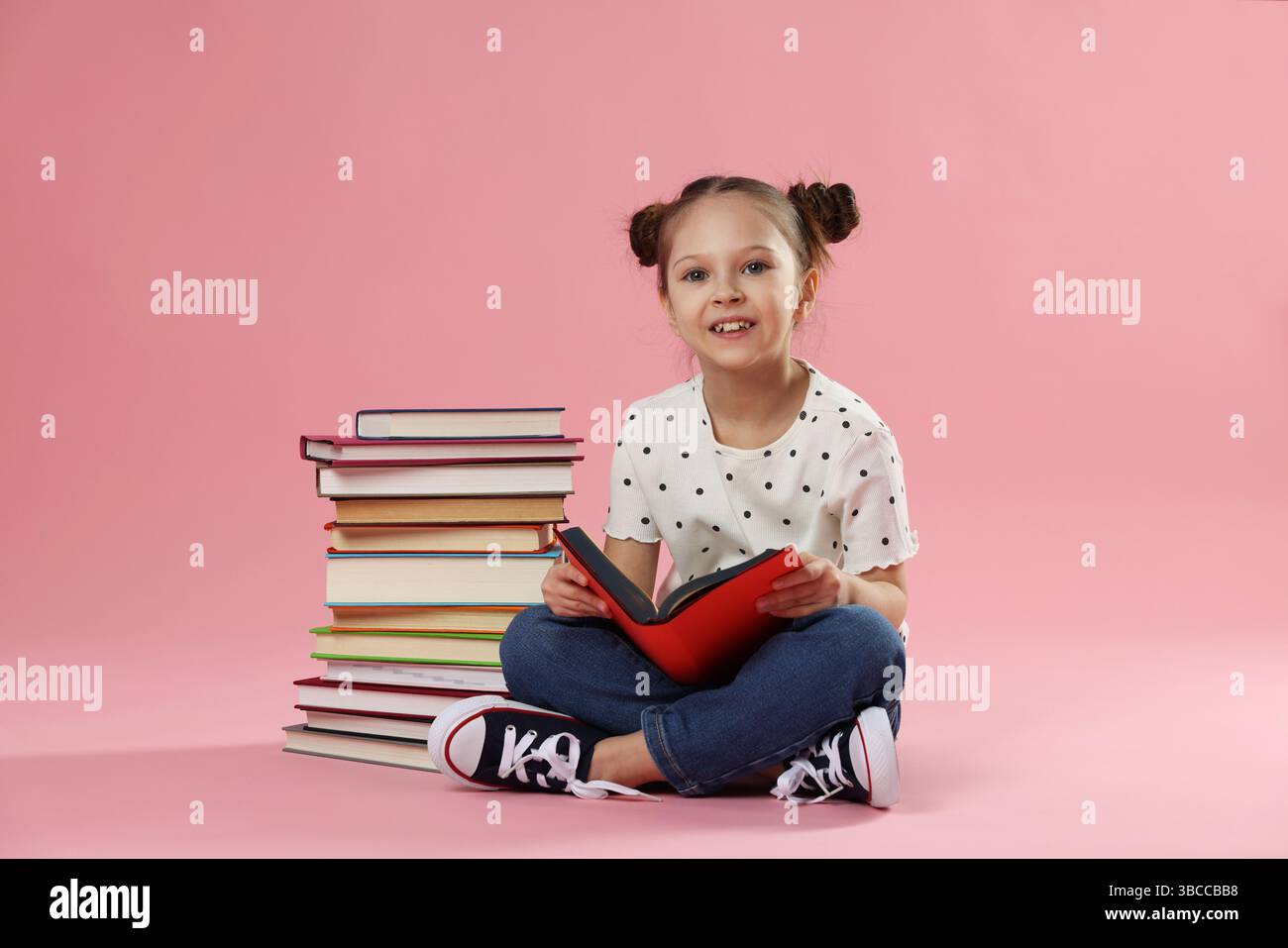 Cute girl with books on pink background Stock Photo - Alamy