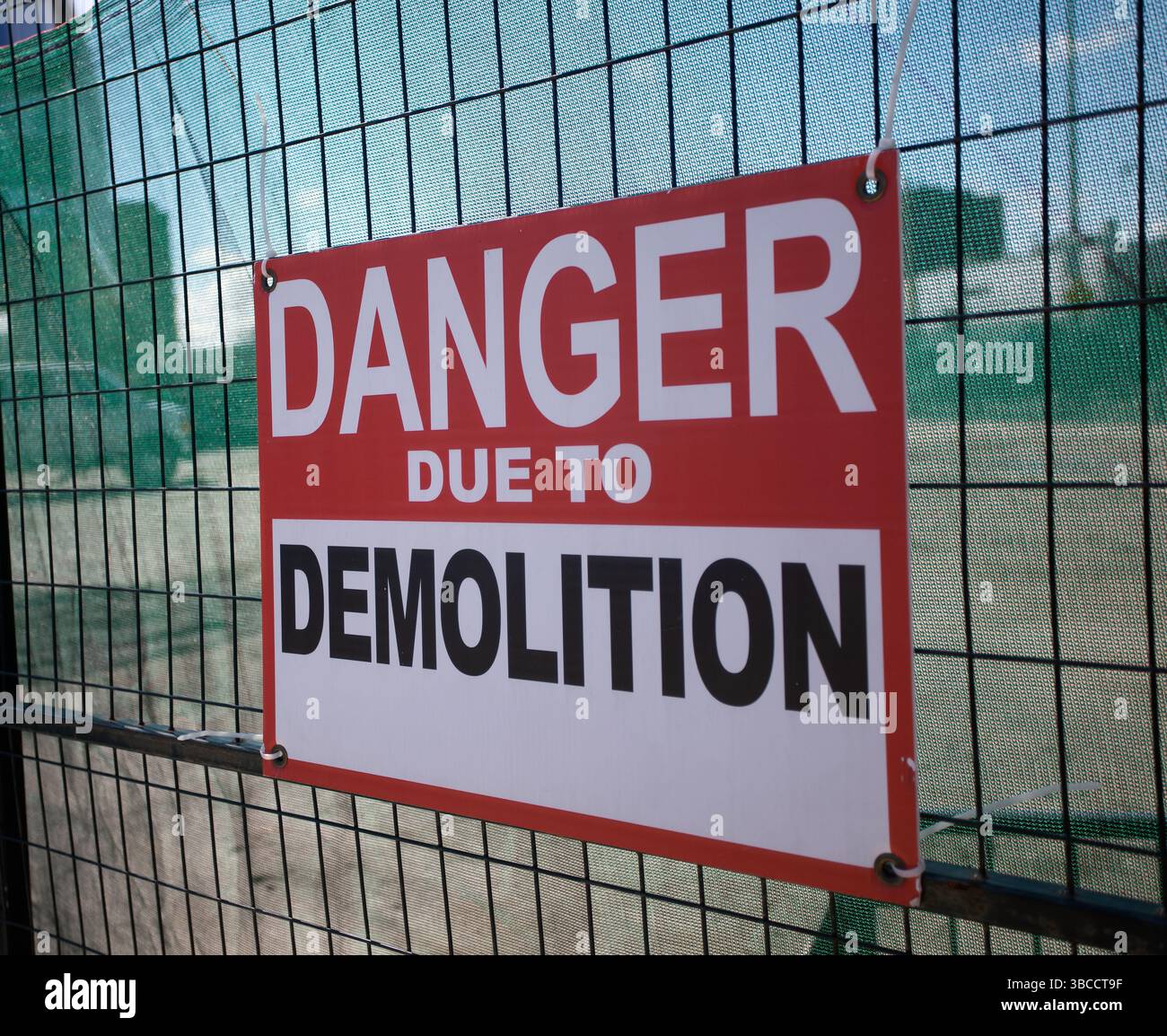 A warning sign reading Danger Due to Demolition is posted on a wire ...