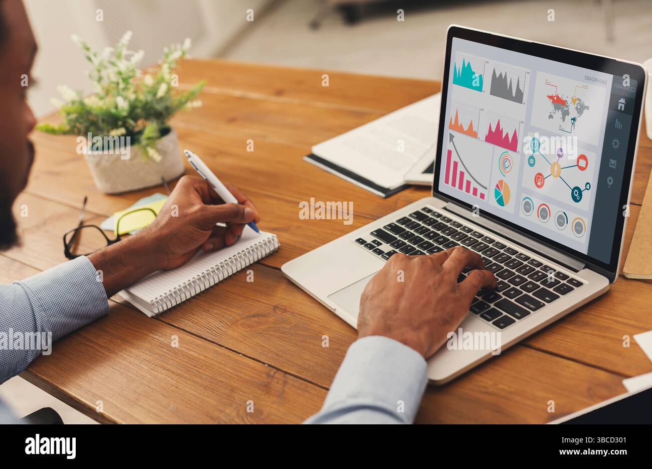 Black entrepreneur analyzing graph on laptop at workplace Stock Photo