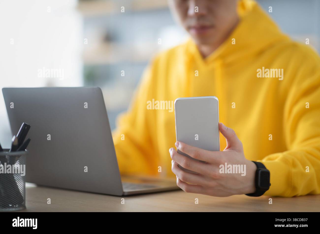 Asian man sitting at desk using cell phone Stock Photo